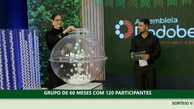 Sorteio manual real da Rodobens: bolinha numerada sendo retirada do globo característico em assembleia