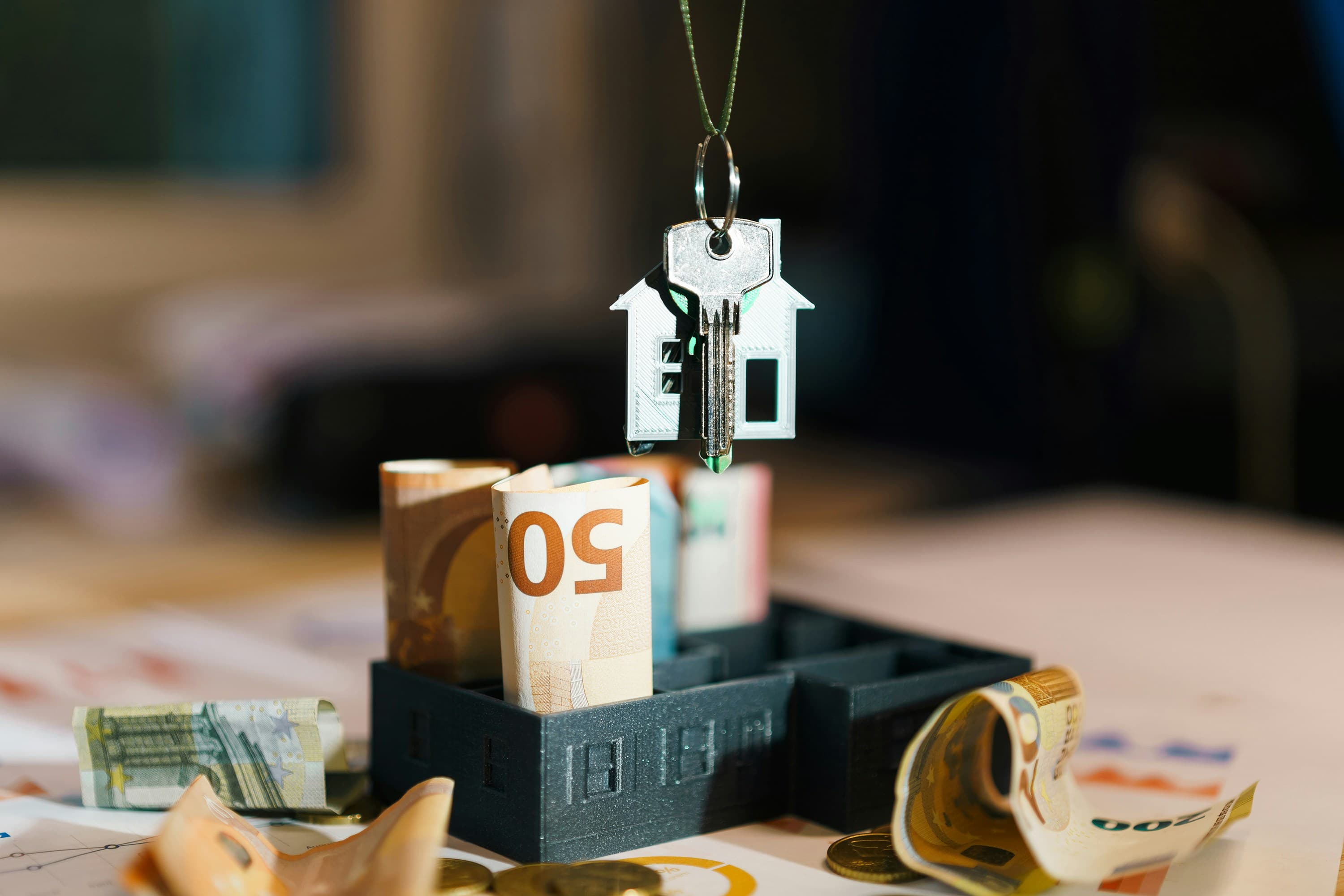 Casa em miniatura suspensa por um fio sobre uma pilha de dinheiro